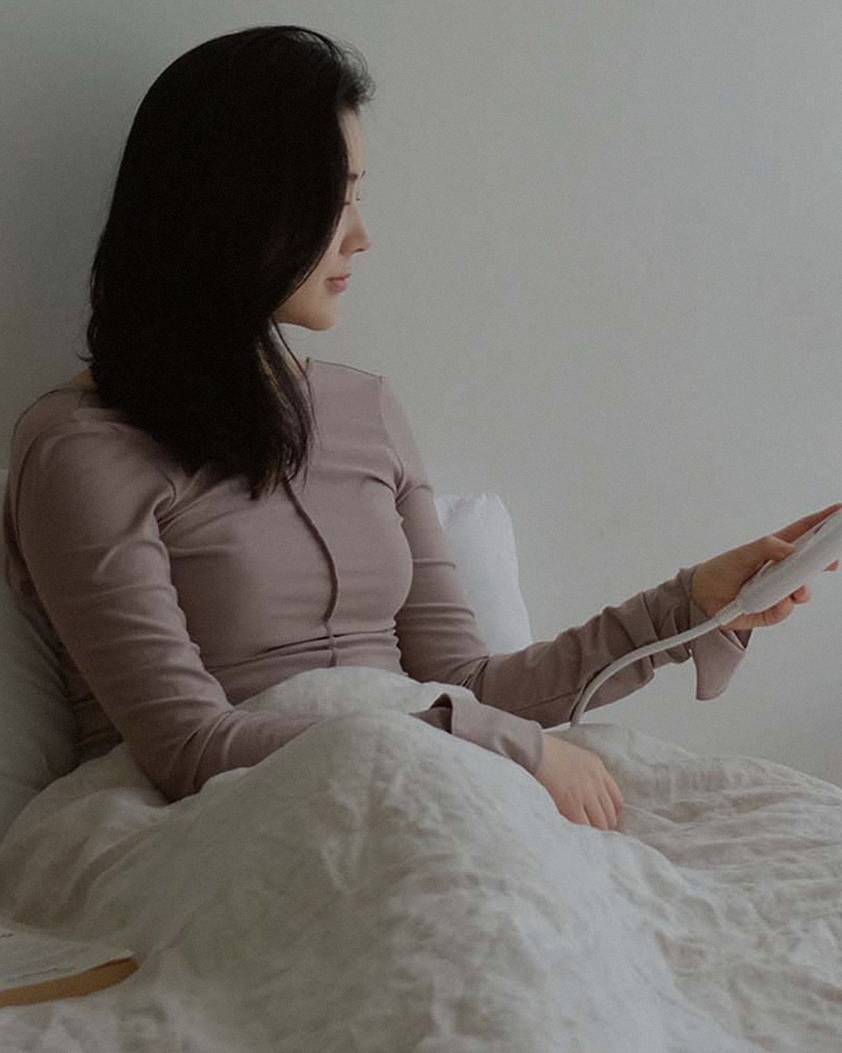 Min sitting up in bed in the morning, the Litual controller in her hand