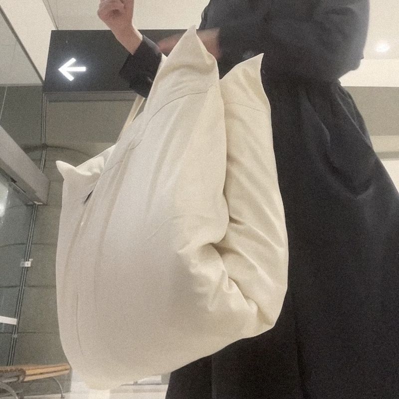 A traveller in a dark coat carrying the Litual bag through an airport