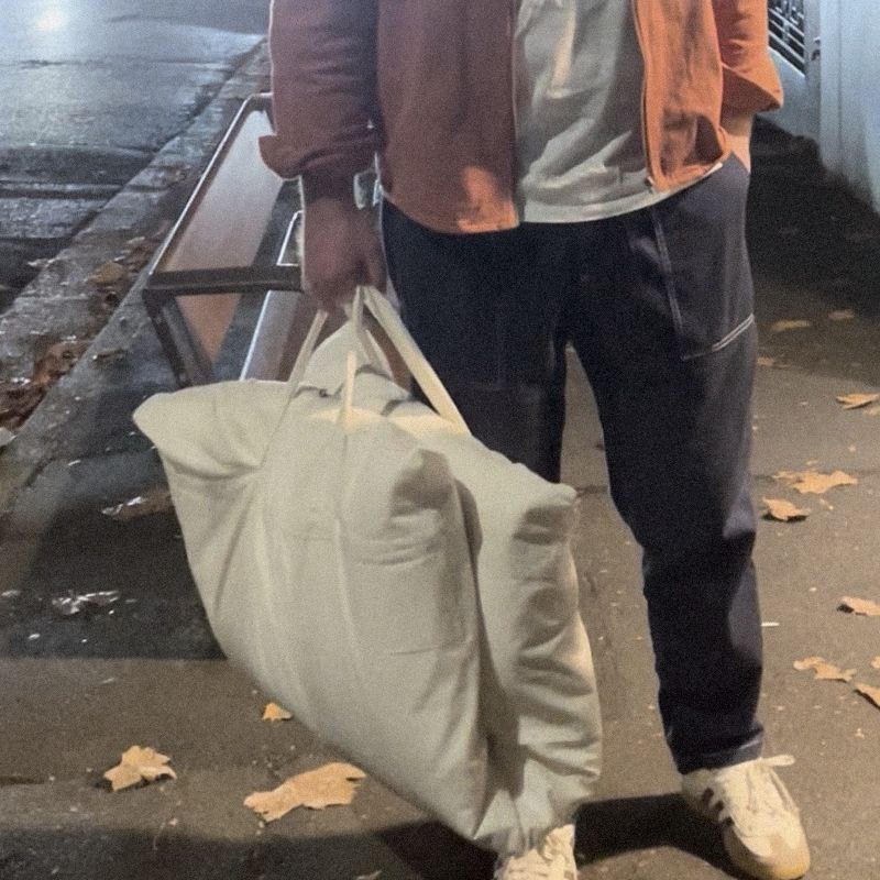 A man on a night street, away for the weekend, holding a Litual bag