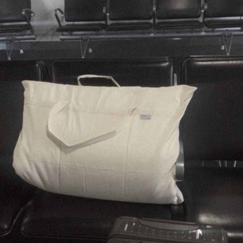 A Litual bag resting on a row of black airport seats beside a suitcase