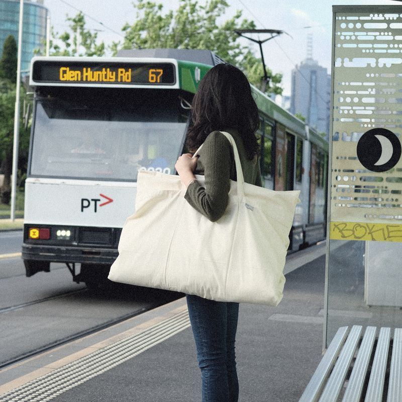 A woman at a Melbourne tram stop with a Litual bag over her shoulder