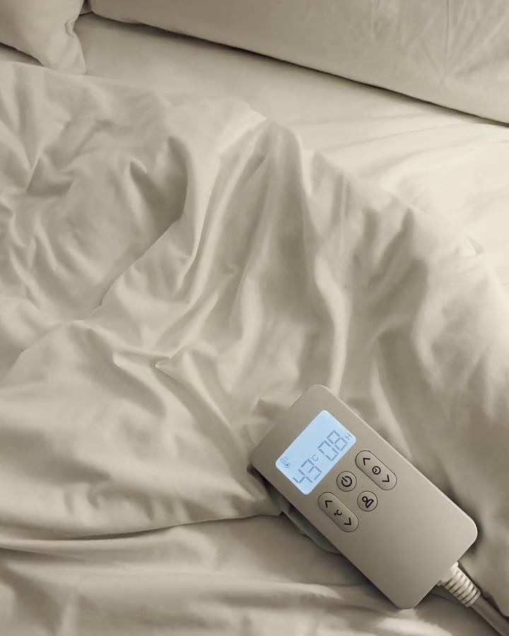 The Litual controller resting on a rumpled sheet, the screen showing 43°C and eight hours