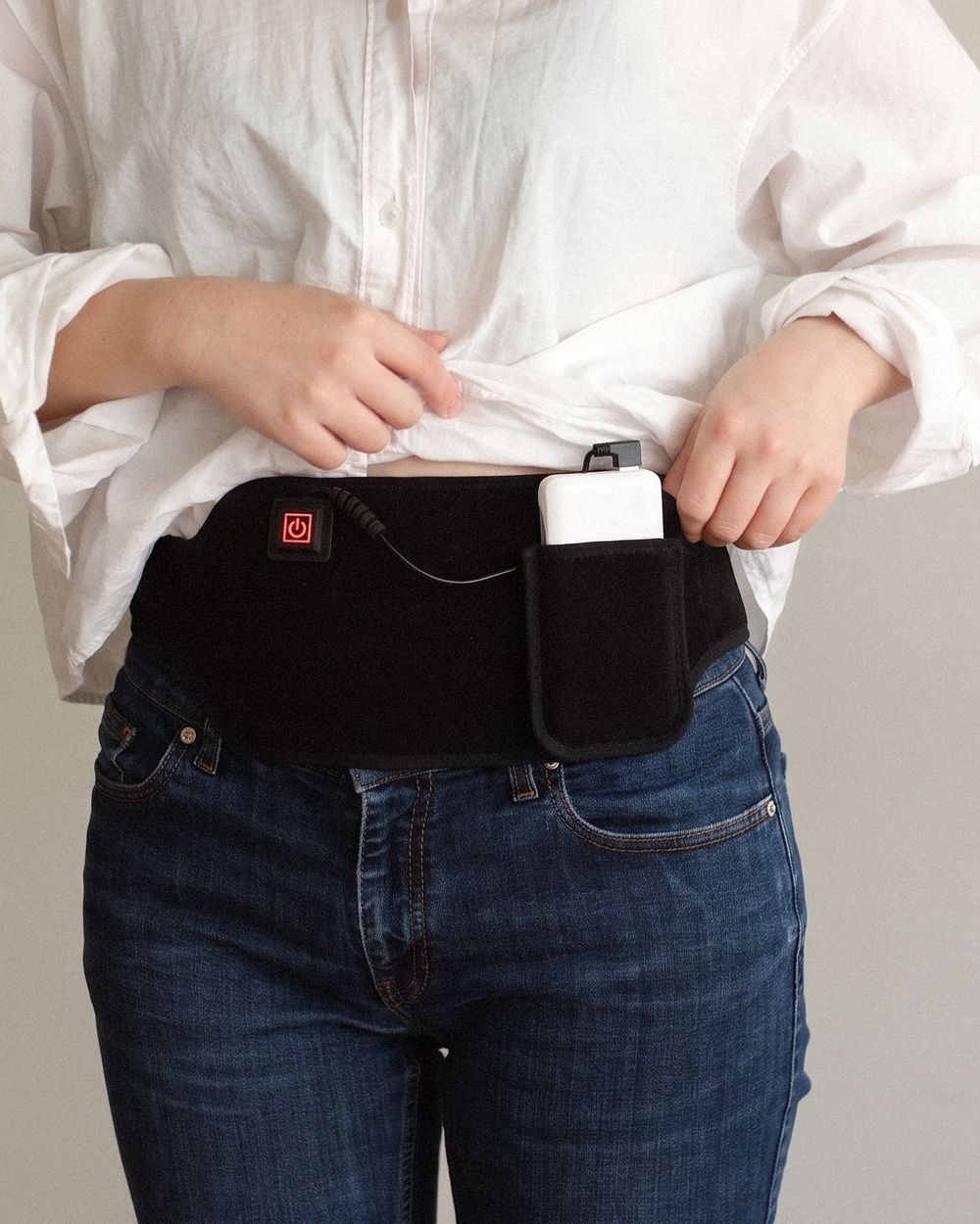 Poom worn low across the belly, the shirt lifted to show the button and the power bank in its pocket