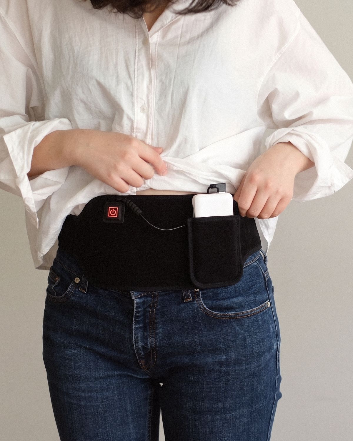 Poom fastened around the waist, the shirt held up: button, cable and power bank all visible