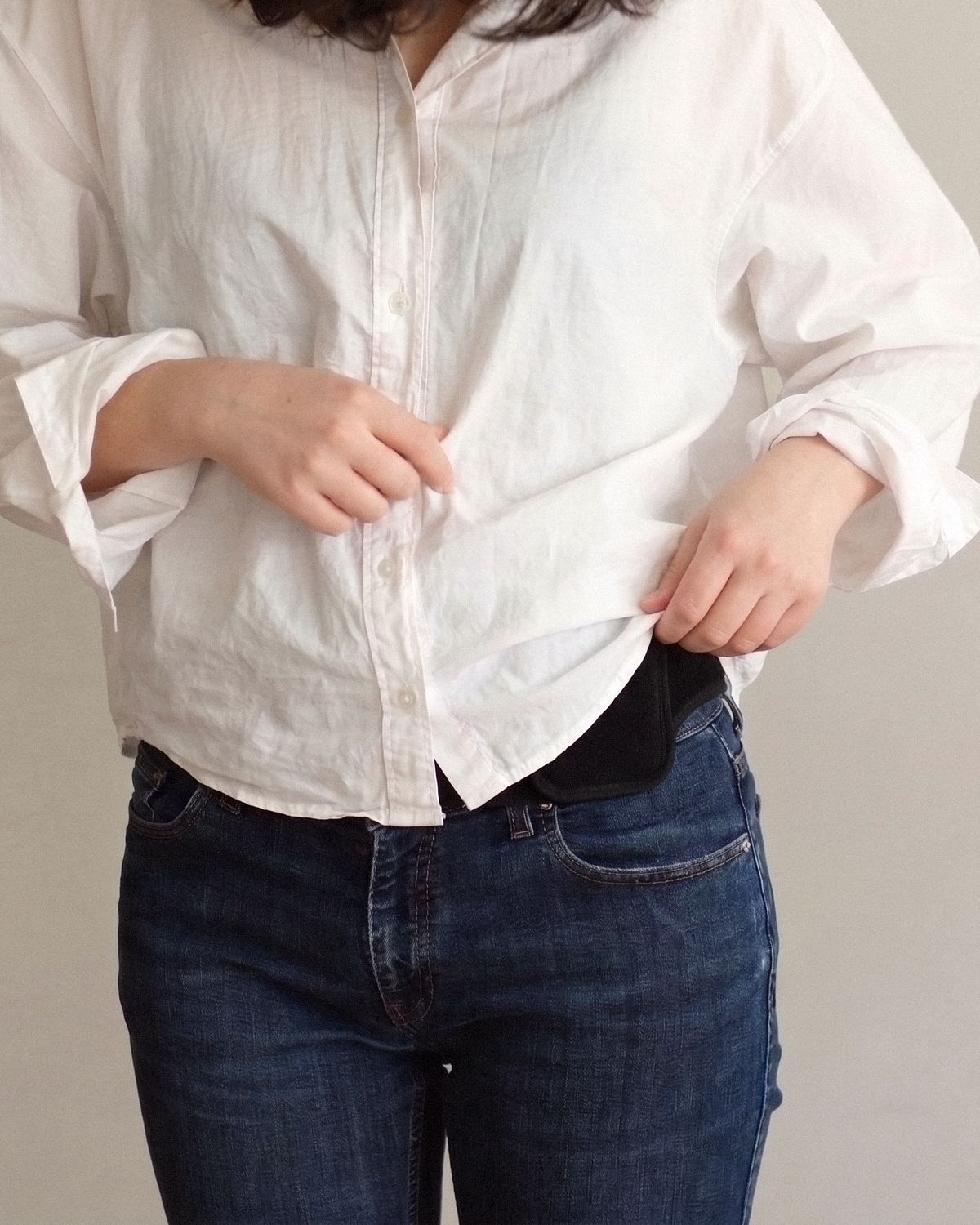 The shirt half lowered, only the edge of the pocket still showing